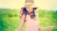 Beautiful happy woman in hat on summer meadow